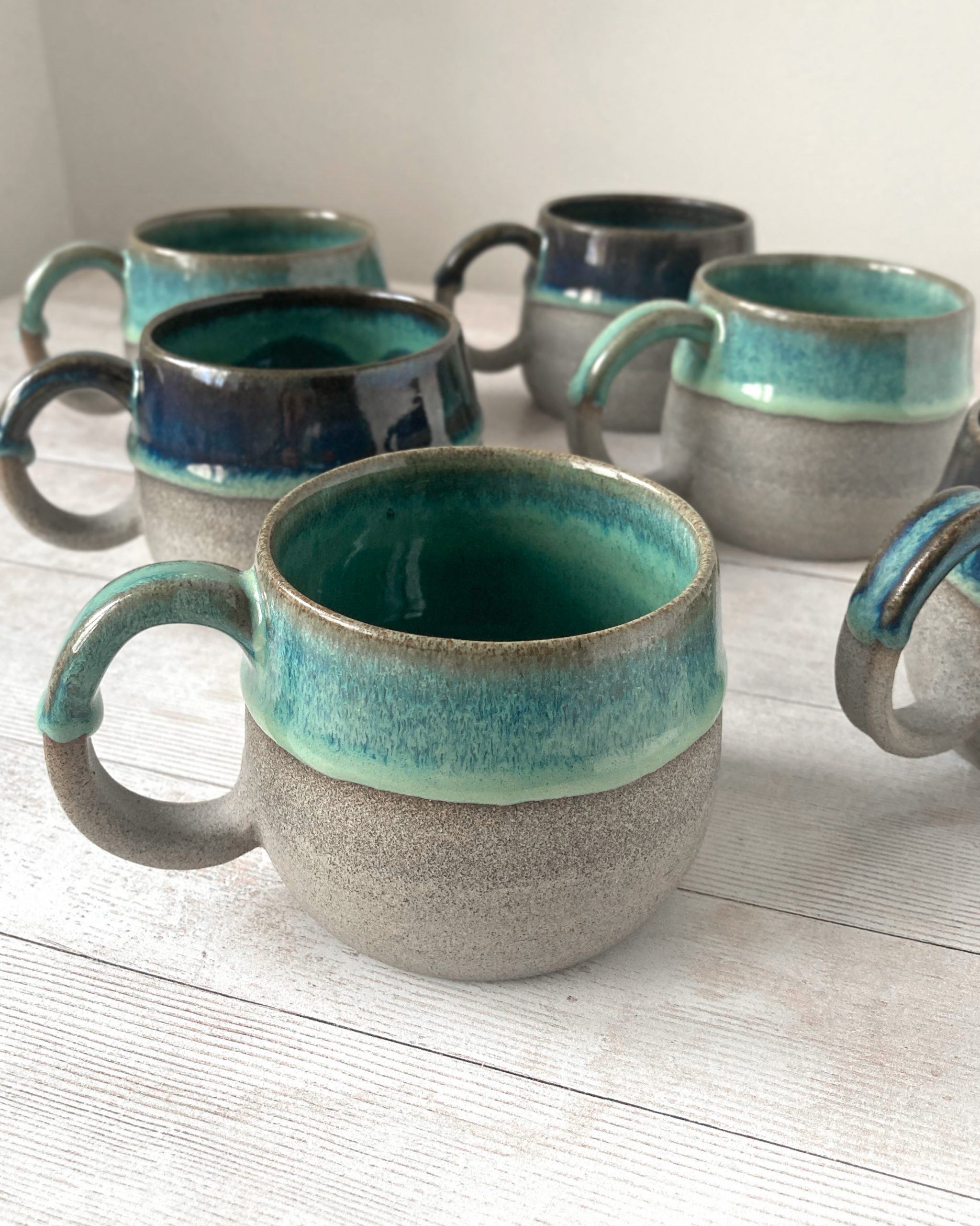 Handmade ceramic coffee mug. Grey stoneware with reactive green glazes